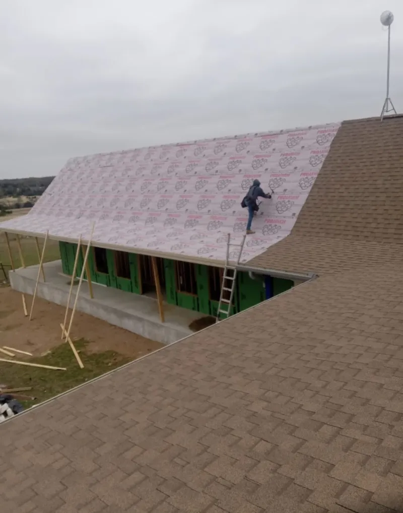 Worker preparing underlayment for a metal roof installation in Fayetteville